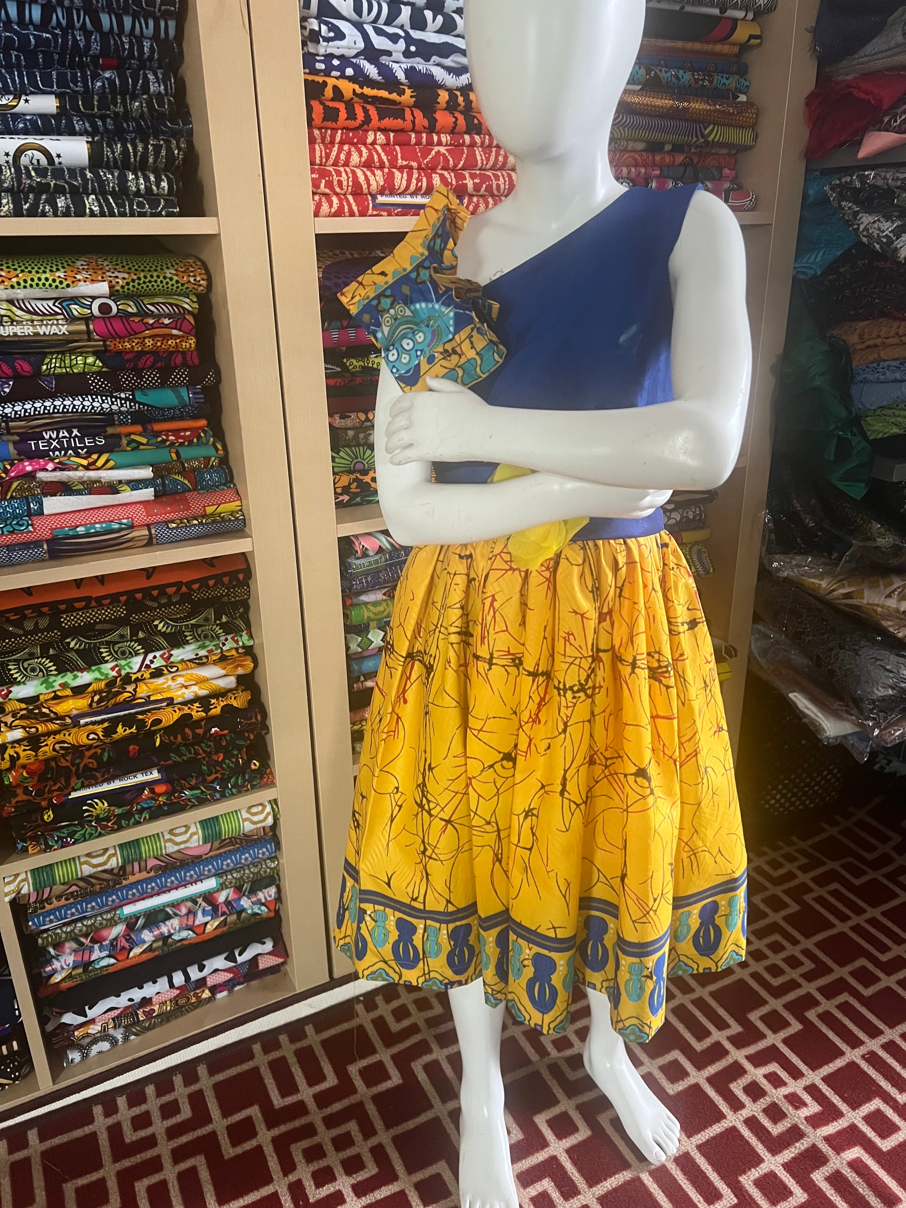 A children's dress designed for ages 7 to 10, featuring coordinating taffeta and Ankara fabric, finished with a stylish knot  at the back.