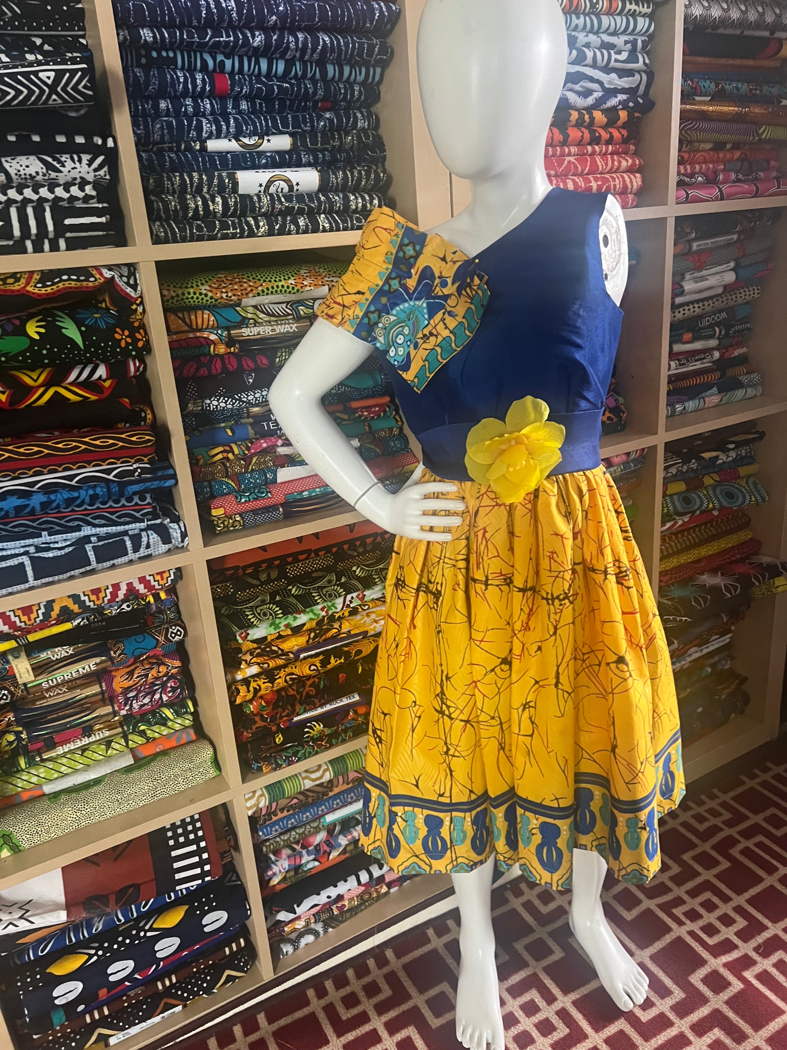 A children's dress designed for ages 7 to 10, featuring coordinating taffeta and Ankara fabric, finished with a stylish knot  at the back.