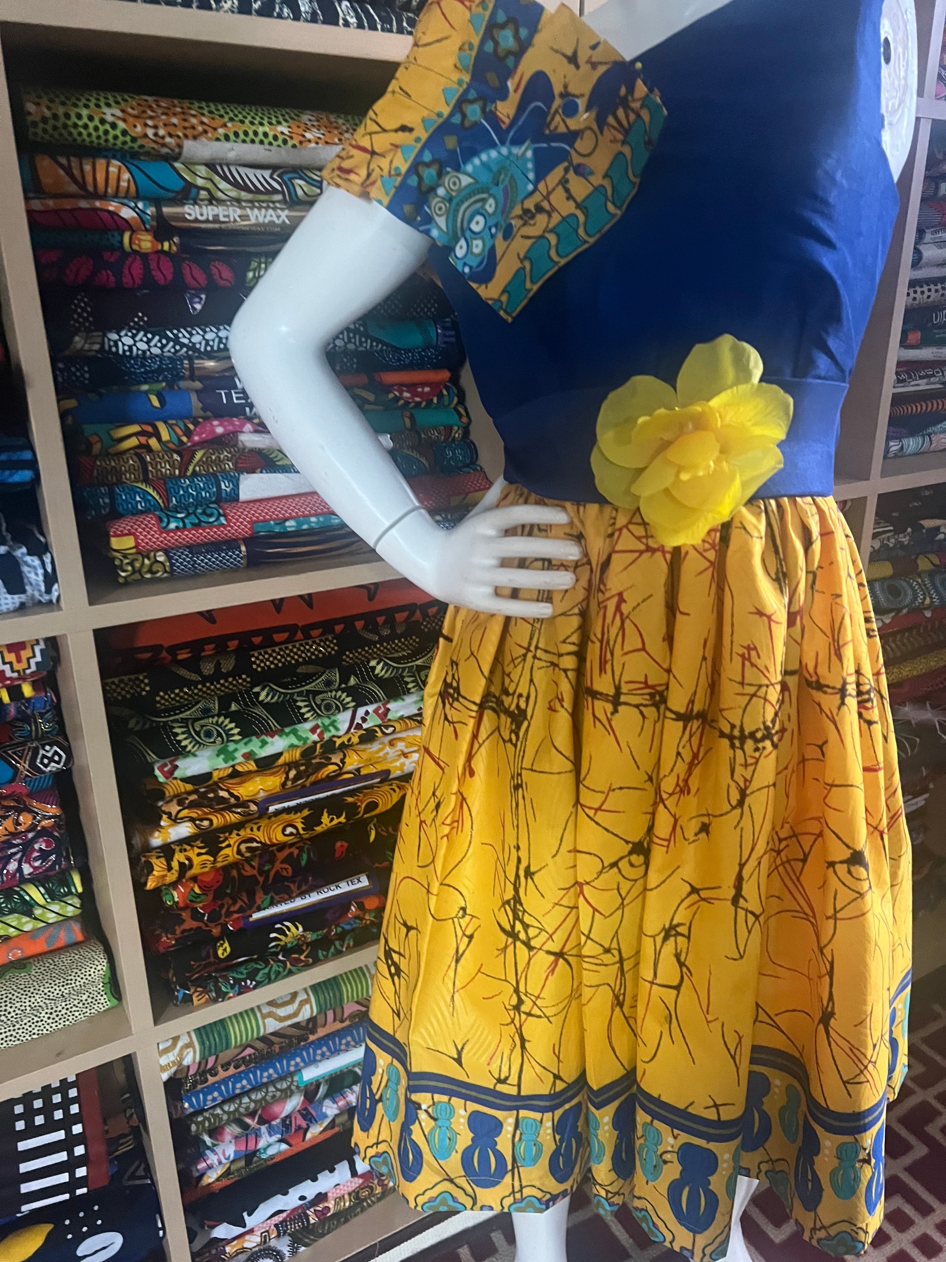 A children's dress designed for ages 7 to 10, featuring coordinating taffeta and Ankara fabric, finished with a stylish knot  at the back.