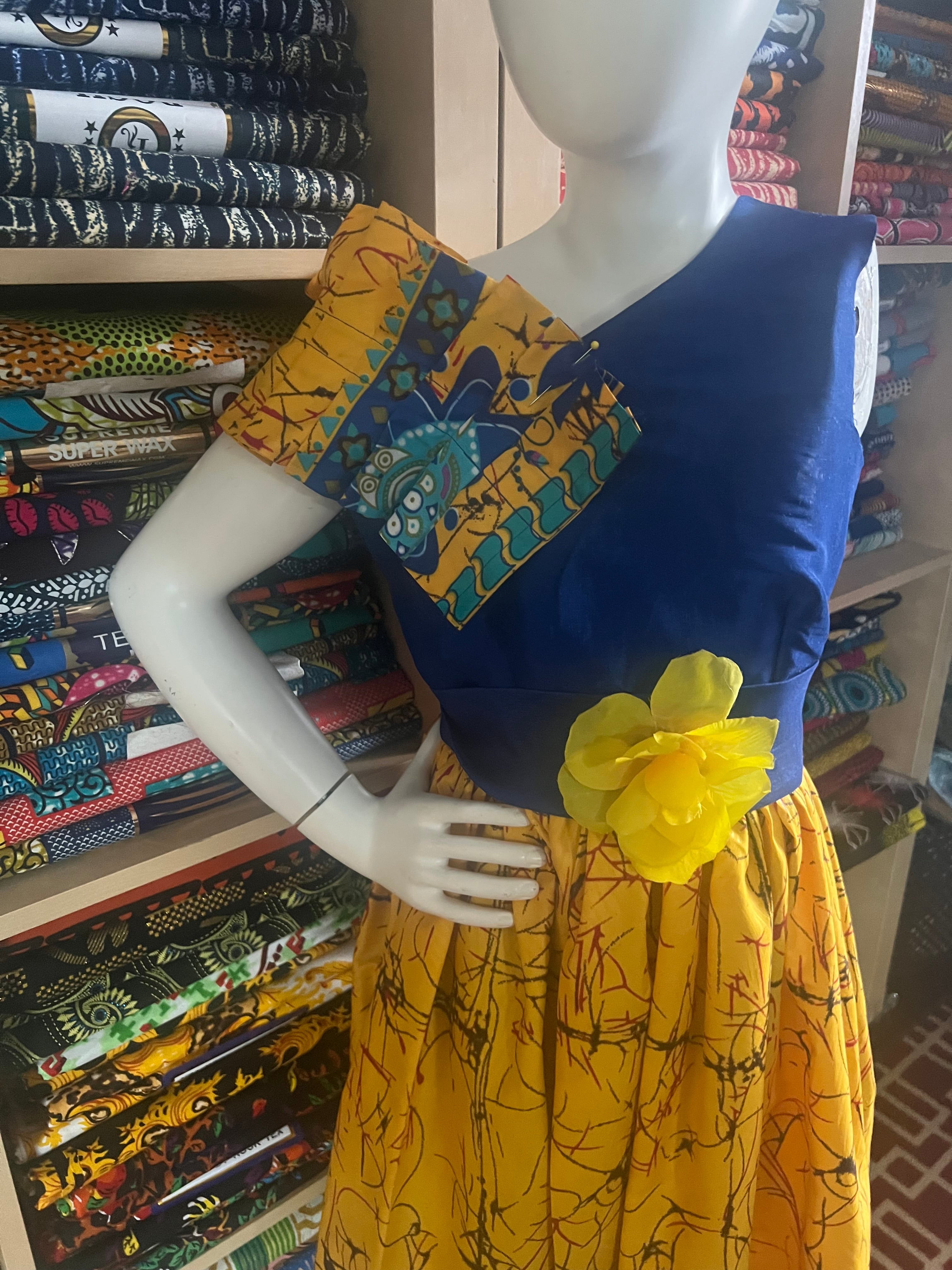 A children's dress designed for ages 7 to 10, featuring coordinating taffeta and Ankara fabric, finished with a stylish knot  at the back.