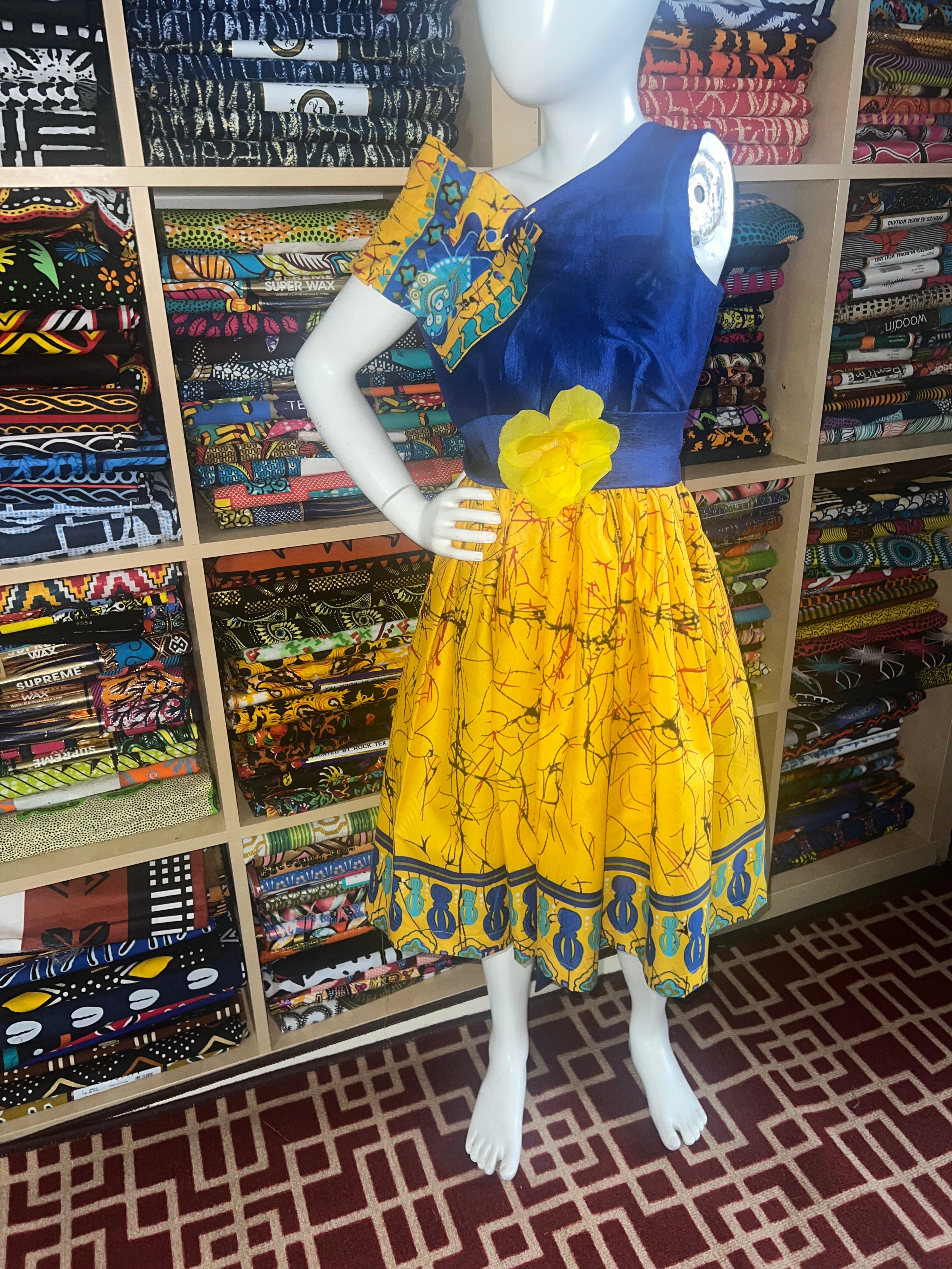 A children's dress designed for ages 7 to 10, featuring coordinating taffeta and Ankara fabric, finished with a stylish knot  at the back.