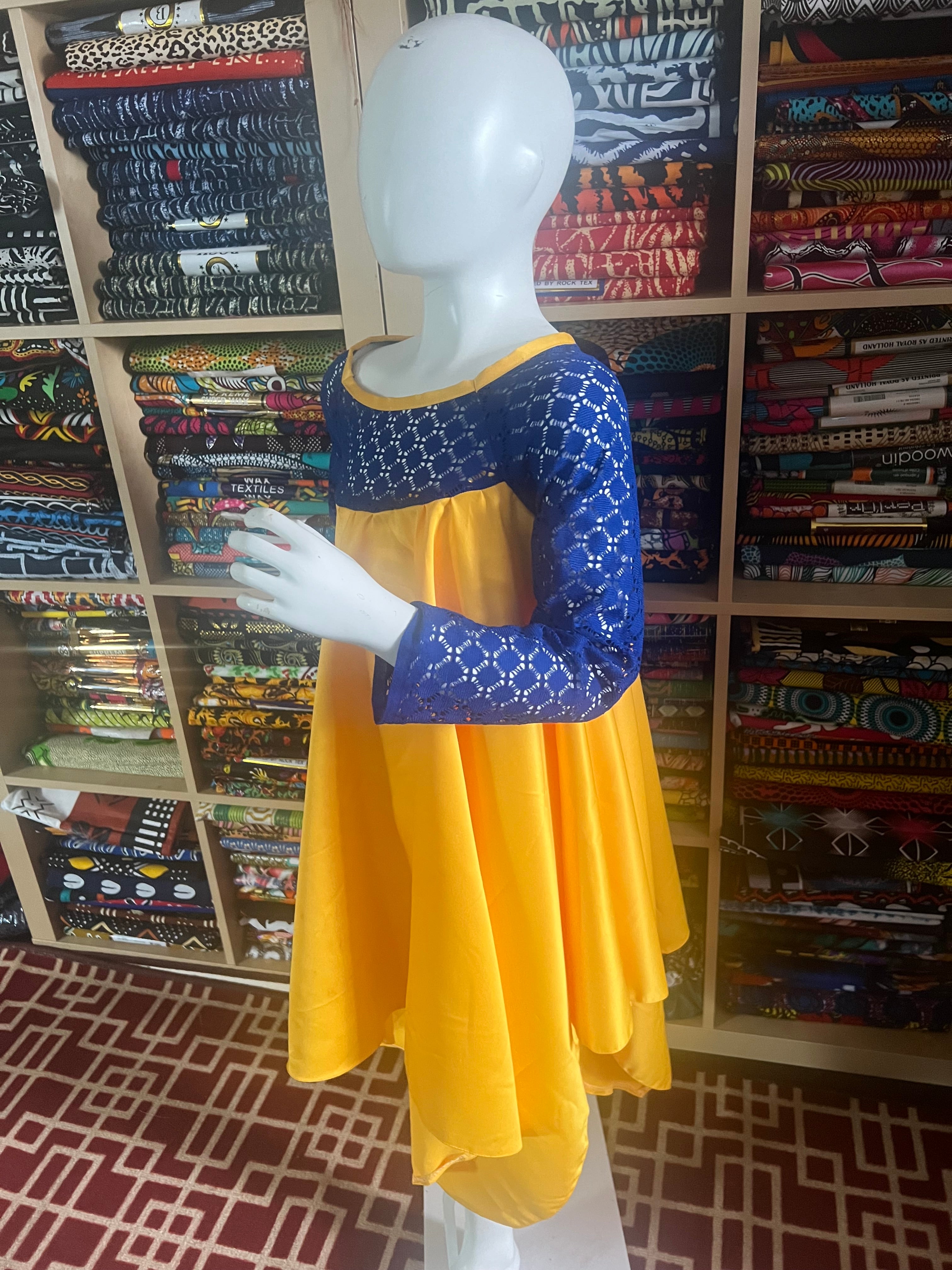 this beautiful Kaba for children is sewn with  yellow  duchess Satine mixed with a blue lace creating a vibrant and eye-catching design.