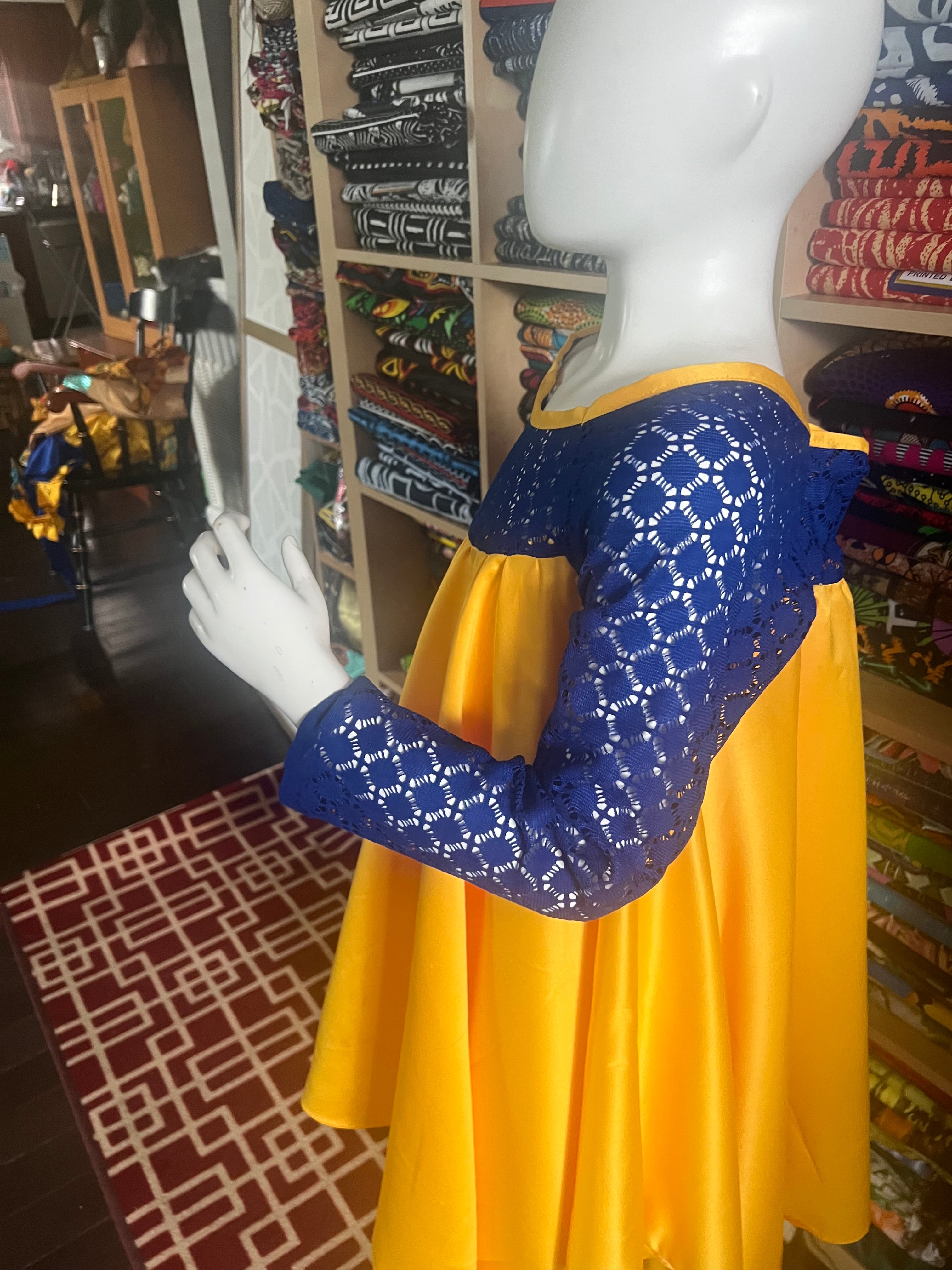 this beautiful Kaba for children is sewn with  yellow  duchess Satine mixed with a blue lace creating a vibrant and eye-catching design.