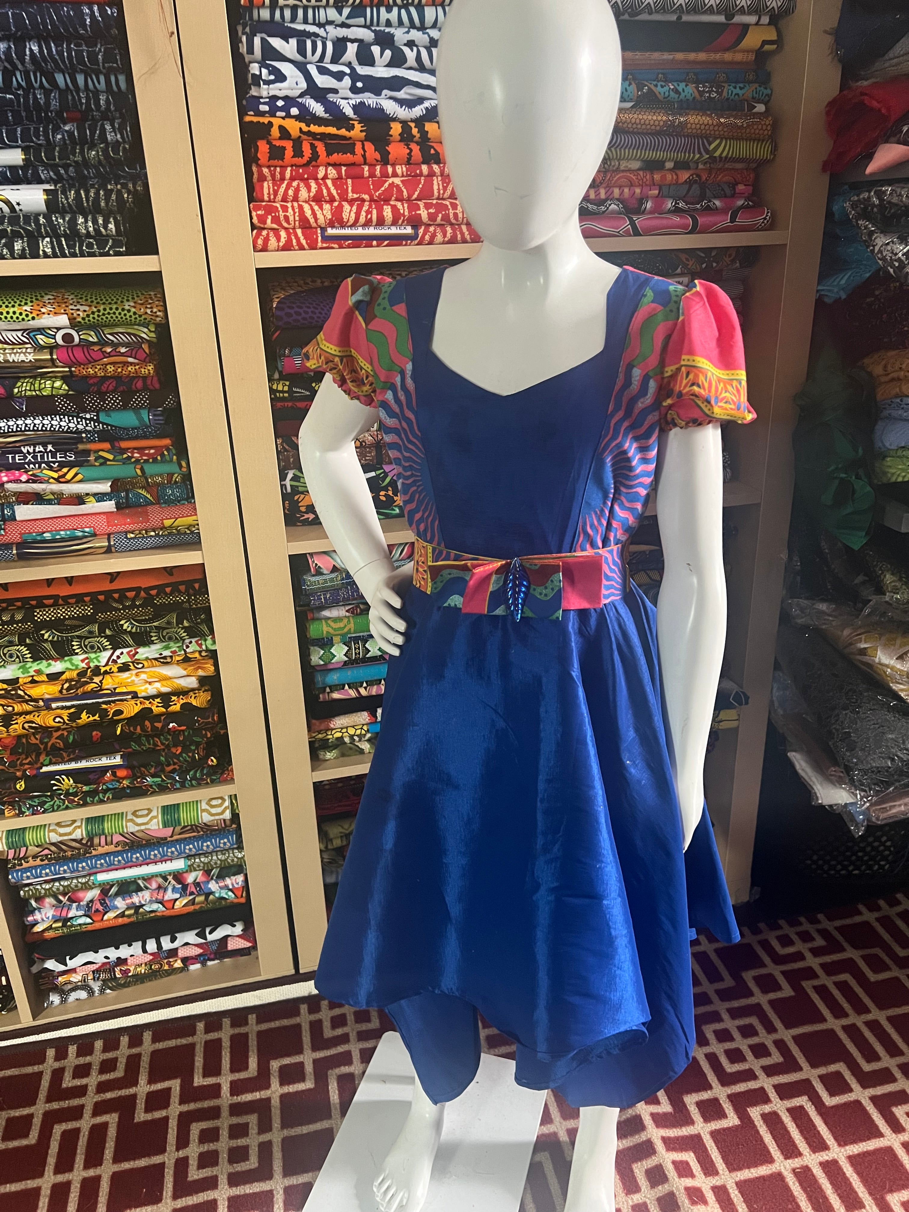 A children's dress designed for ages 7 to 10, featuring coordinating taffeta and Ankara fabric, finished with a stylish knot et the back