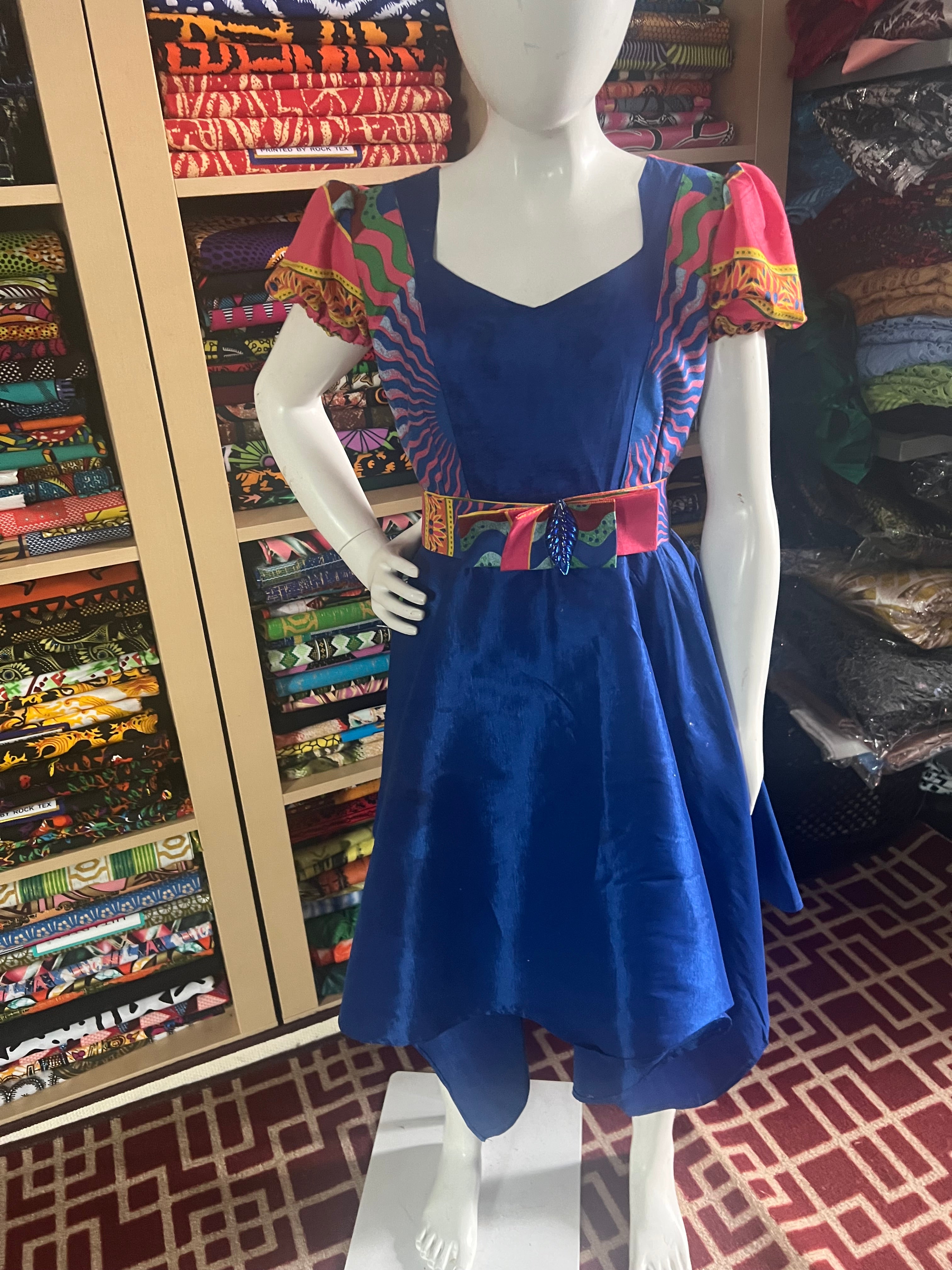 A children's dress designed for ages 7 to 10, featuring coordinating taffeta and Ankara fabric, finished with a stylish knot et the back