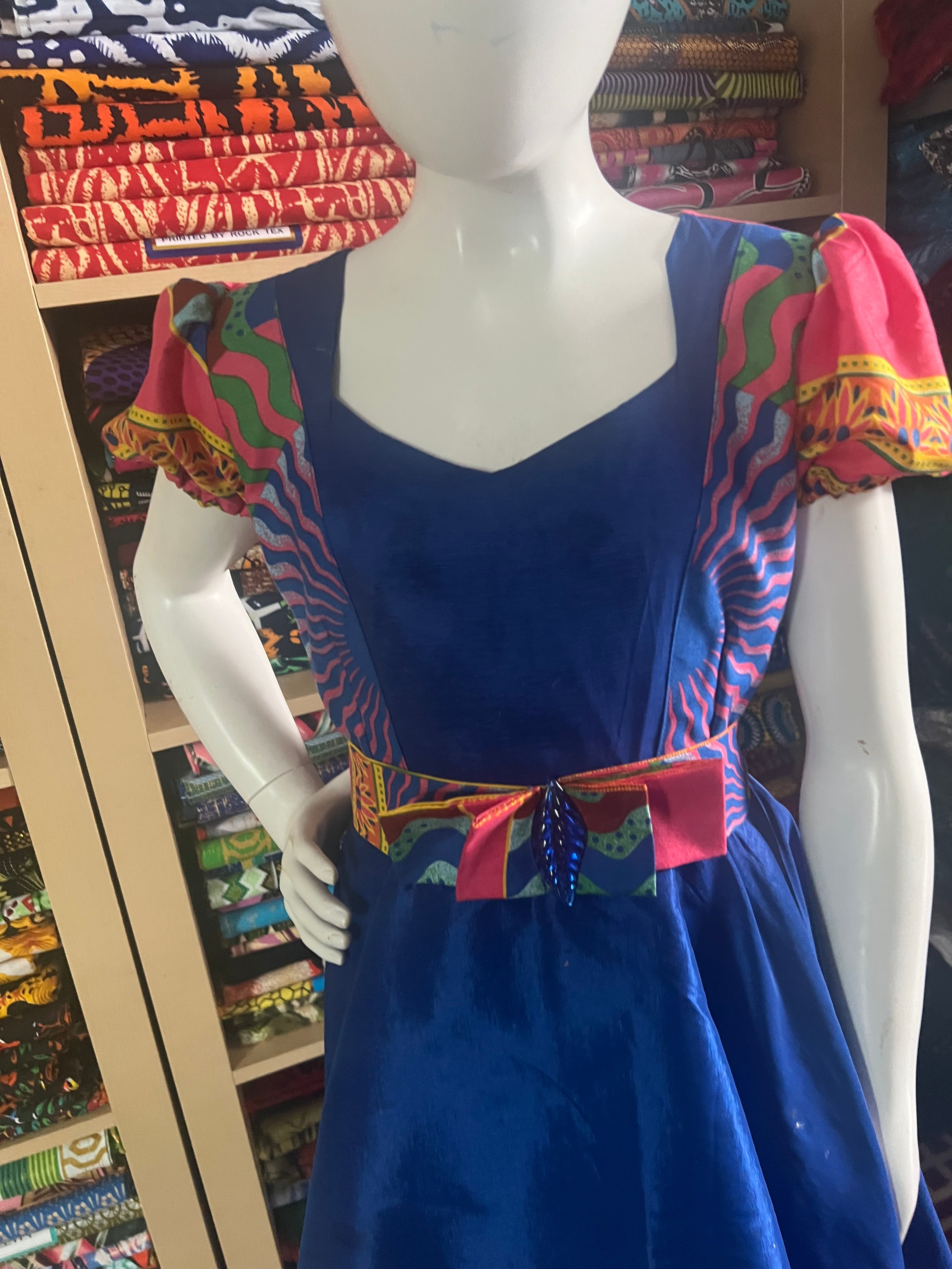 A children's dress designed for ages 7 to 10, featuring coordinating taffeta and Ankara fabric, finished with a stylish knot et the back